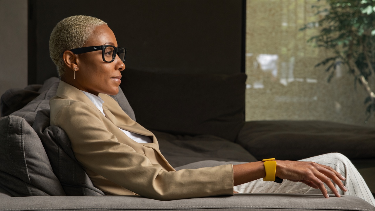 A woman in AI glasses relaxing on a sofa, a yellow TapXR on her wrist