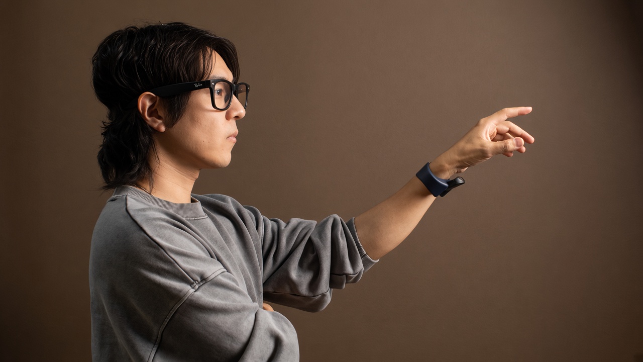 A man wearing AI glasses gestures mid-air, a navy TapXR on his wrist